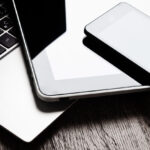 Laptop, tablet, and smartphone on wooden desk